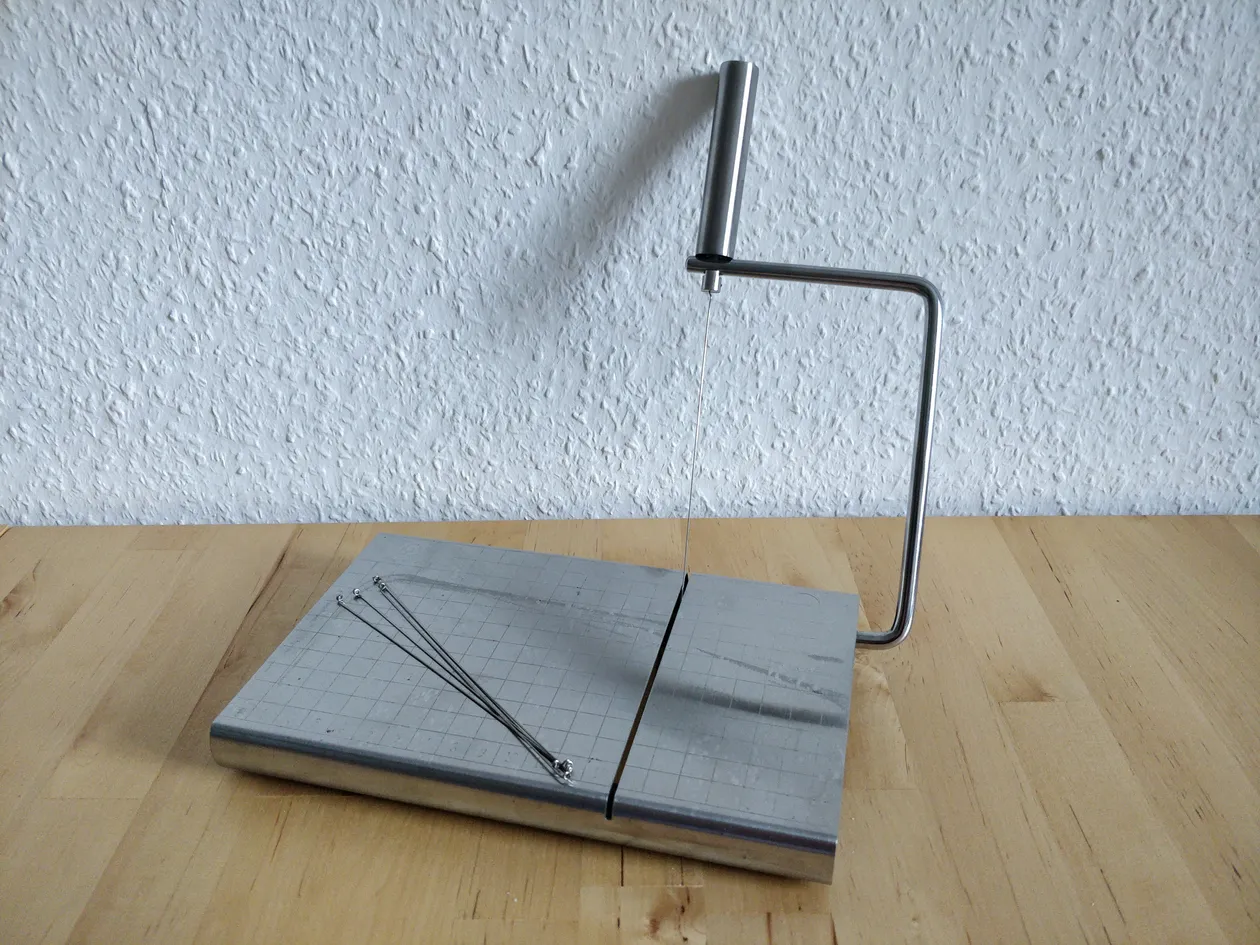An aluminum board. There’s a lever with a wire that can be rotated down so it cuts through what’s lying on the board.